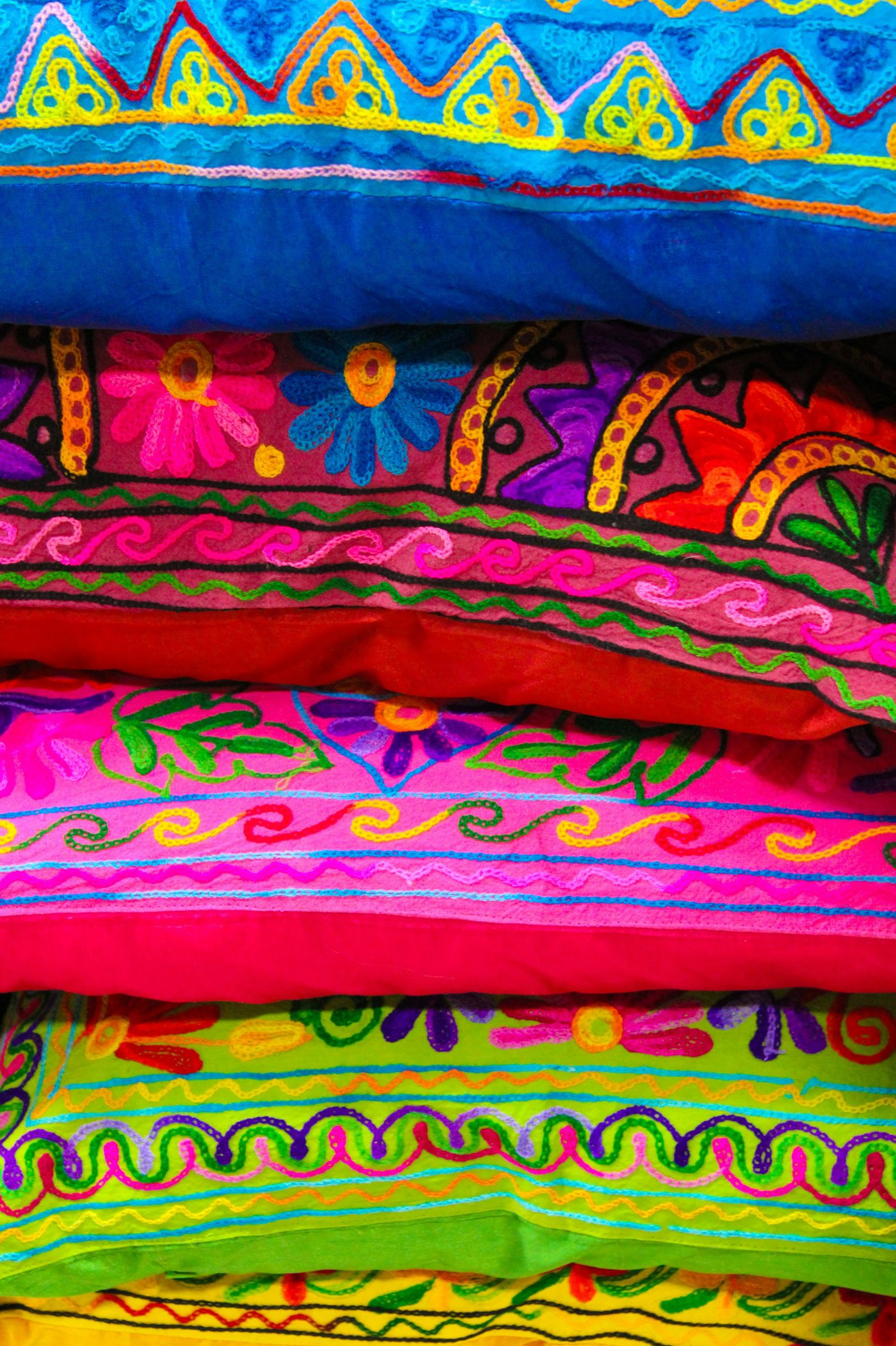 Stack of colourful hand-embroidered cushions with floral chain-stitch patterns